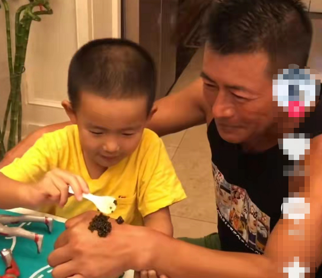 57岁高曙光与儿子吃西餐，儿子身穿黄色t恤笑眼弯弯模样可爱
