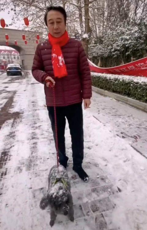 冯巩牵小狗雪地中漫步 穿红色羽绒服配围巾喜庆十足